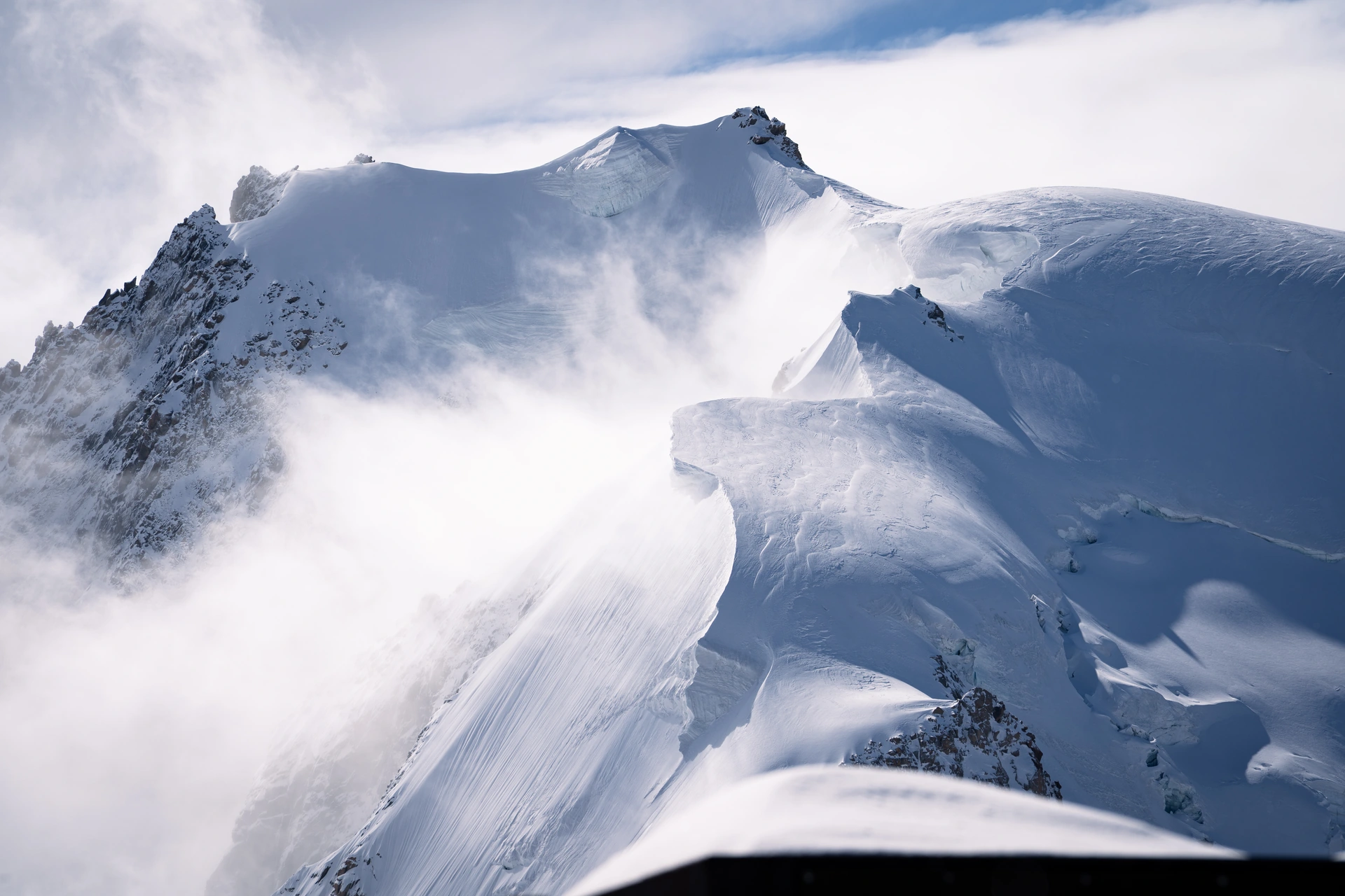 Snow-covered alpine ridges emerging through clouds